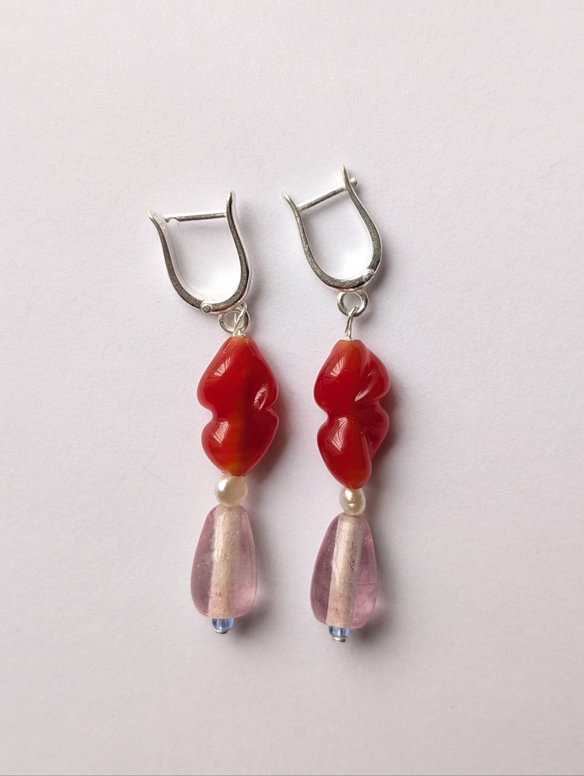 Pair of earrings with red and pink beads on a light gray background