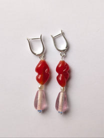 Pair of earrings with red and pink beads on a light gray background