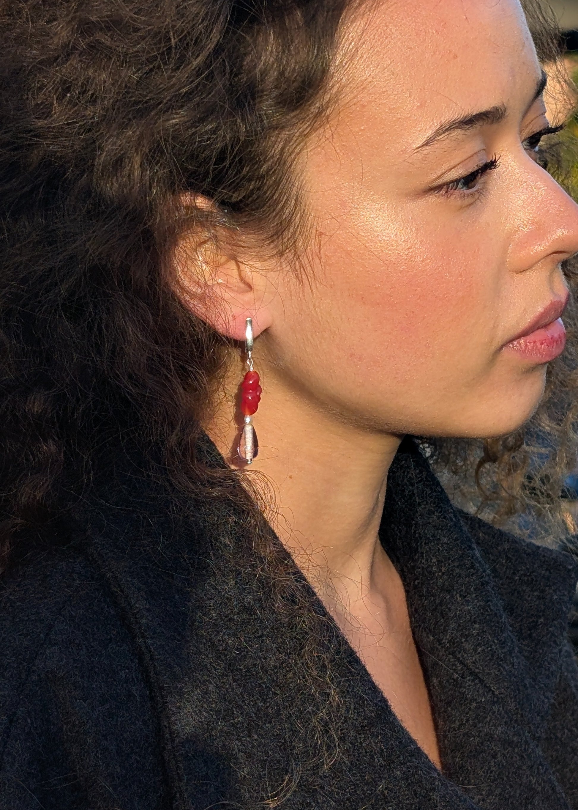 Close-up of a woman wearing red earrings with a blurred background