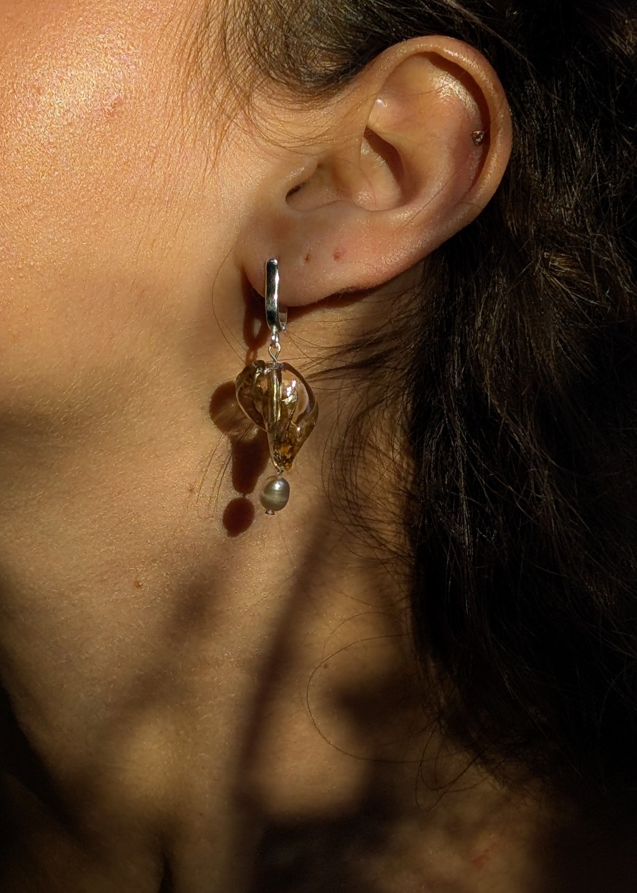 Close-up of an ear with a dangling earring, with a blurred background