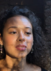 Woman with dark hair and earrings against a dark background