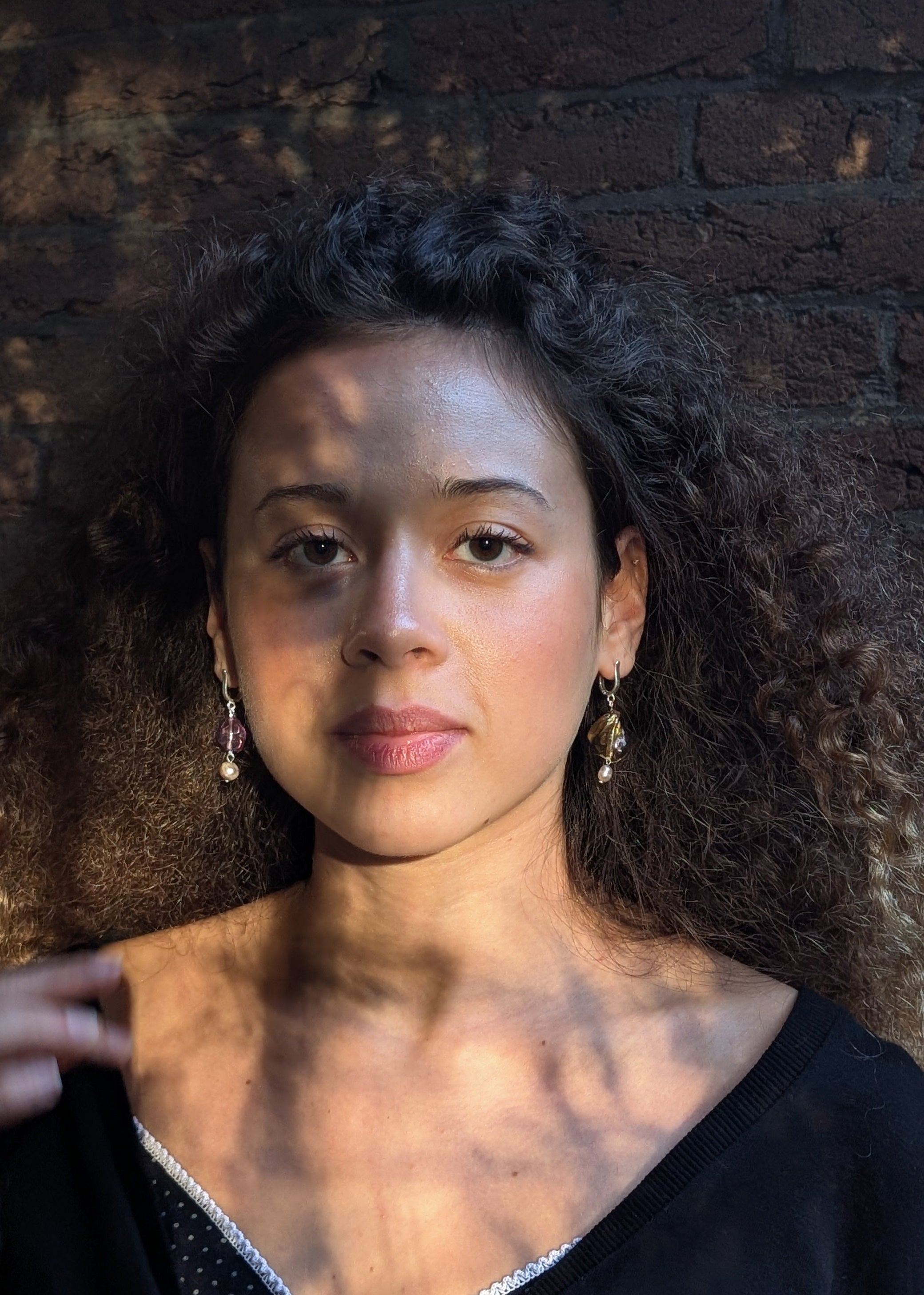 Woman with curly hair against a dark brick wall