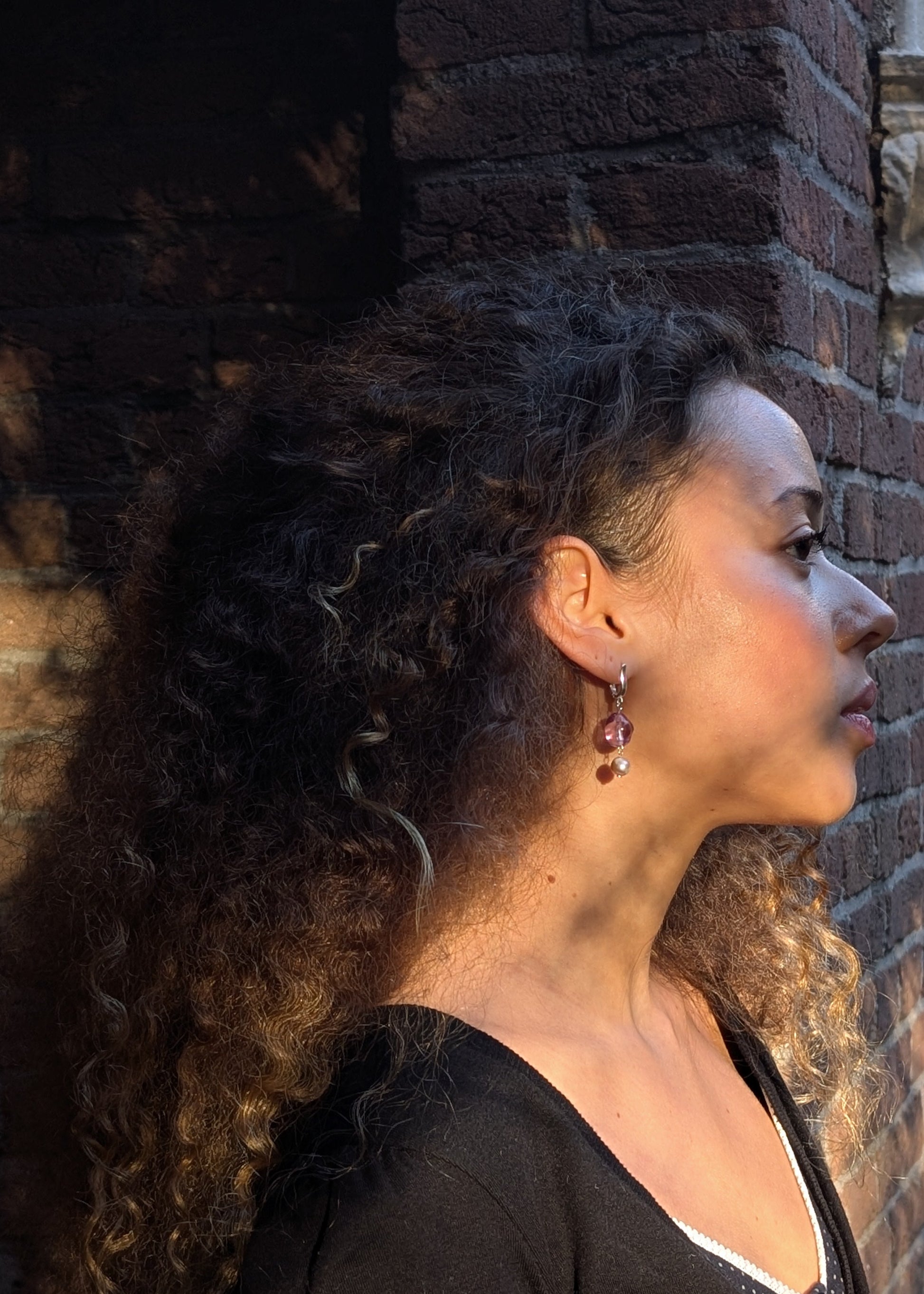 Woman with curly hair leaning against a brick wall