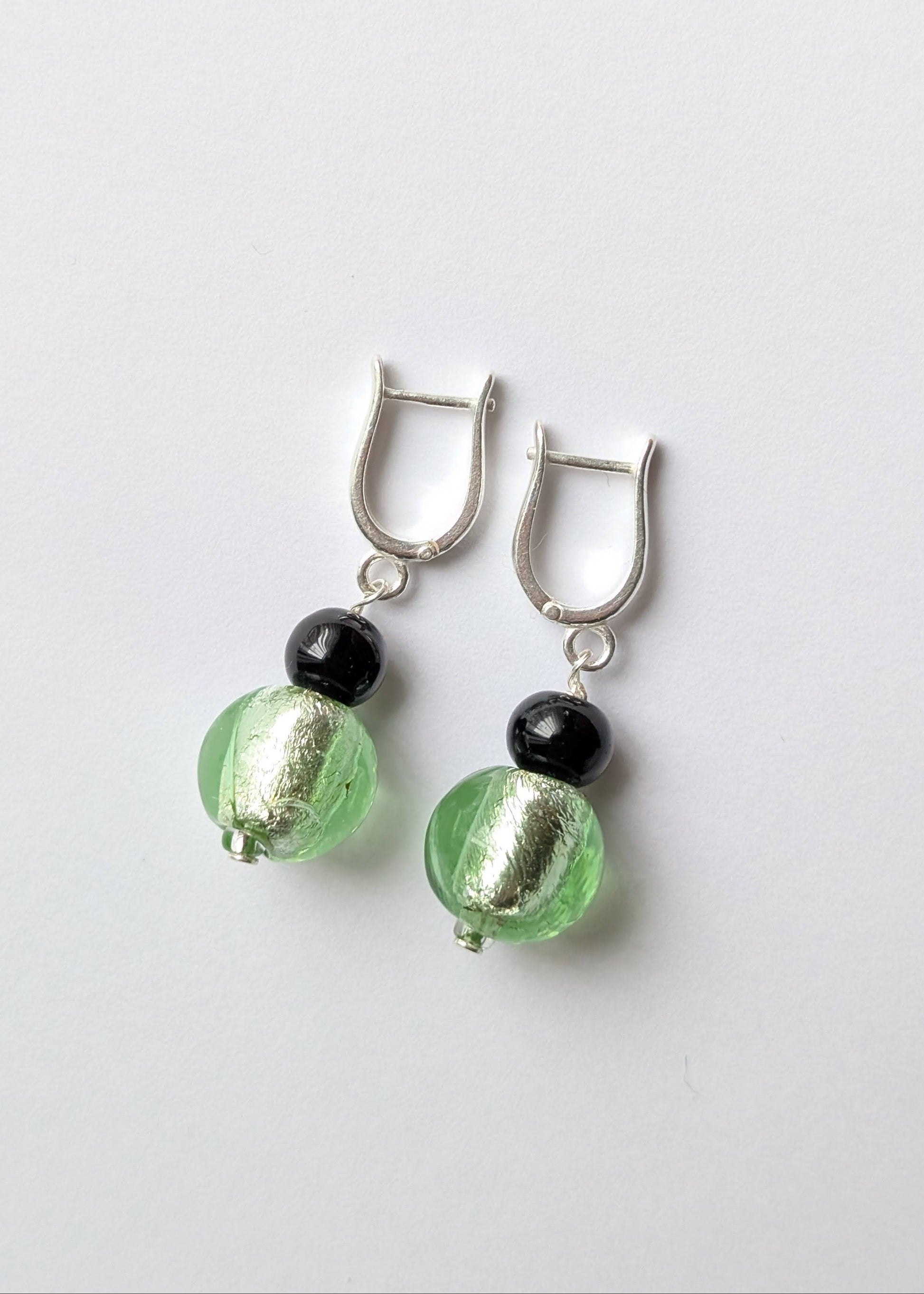 Pair of earrings with green and black beads on a white background