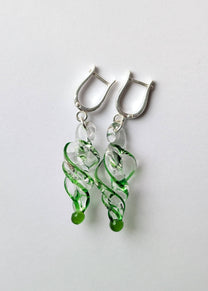 Green and silver earrings on a light gray background