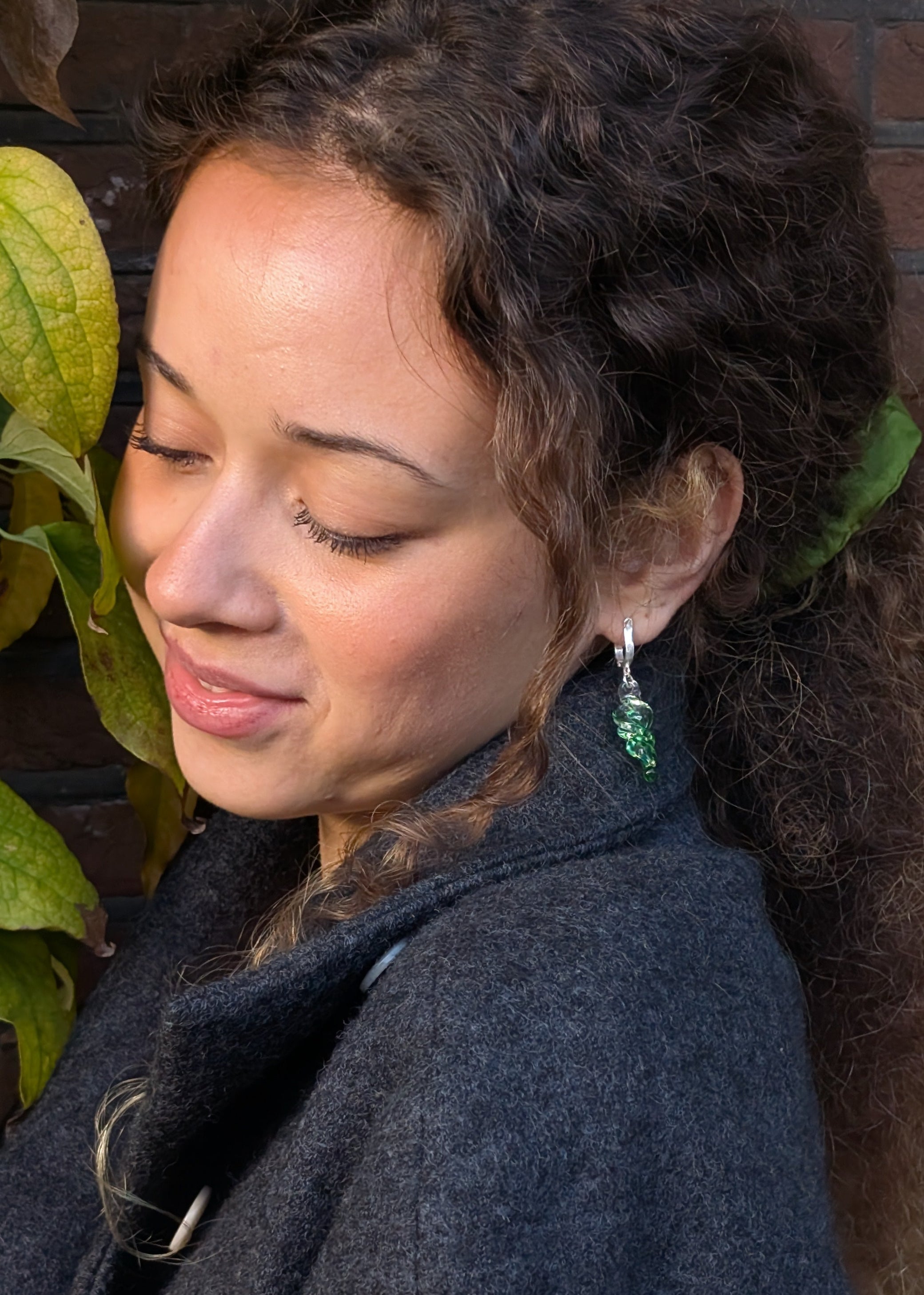 Woman wearing a dark coat with a plant in the background