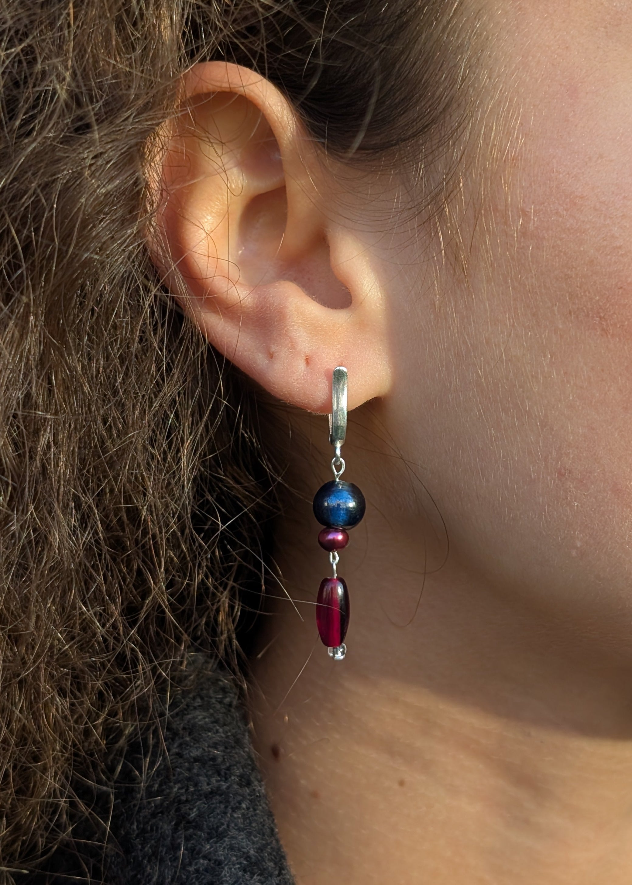 Close-up of an ear wearing a beaded earring with a blurred background