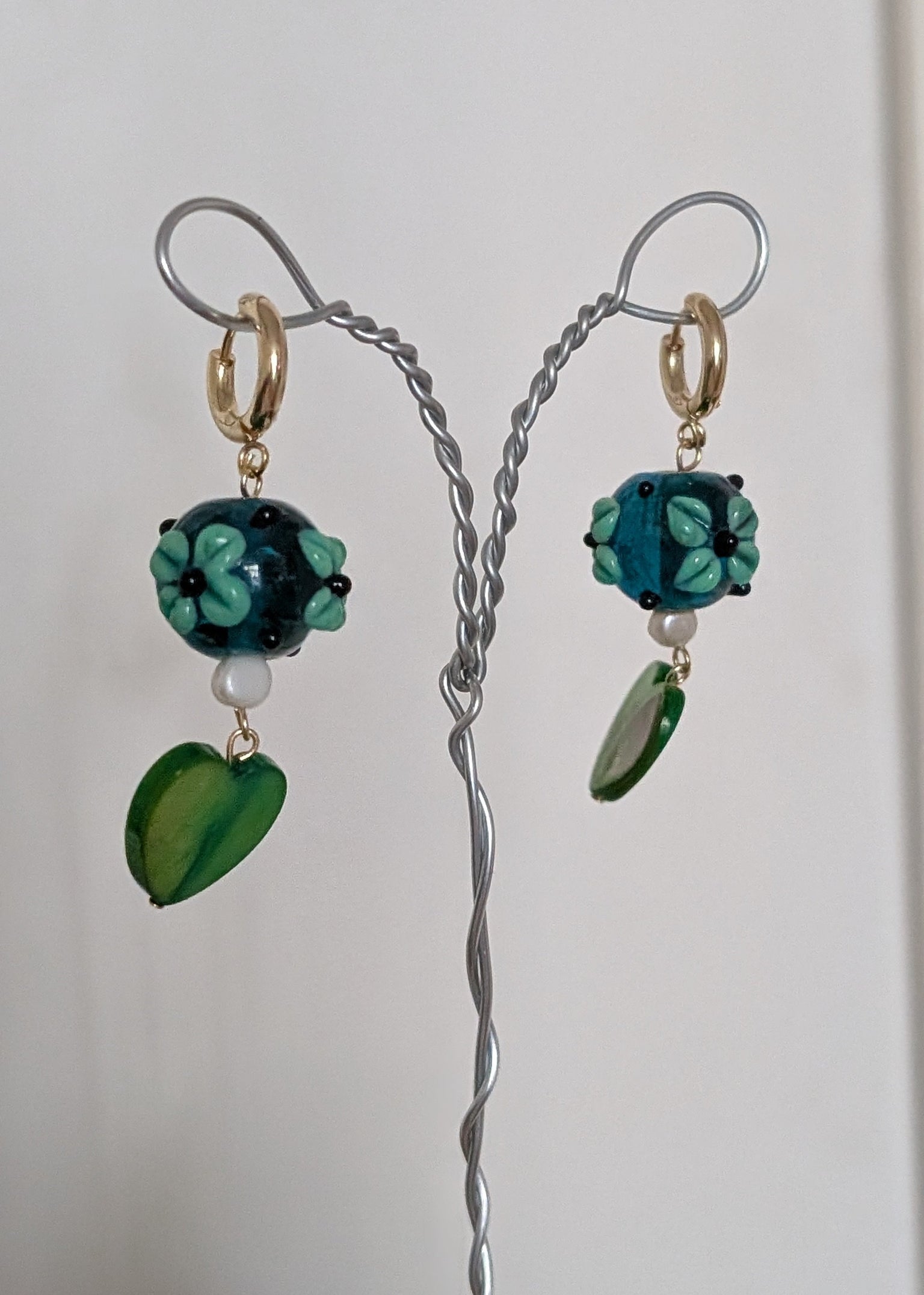 Pair of earrings with green and blue beads on a white background