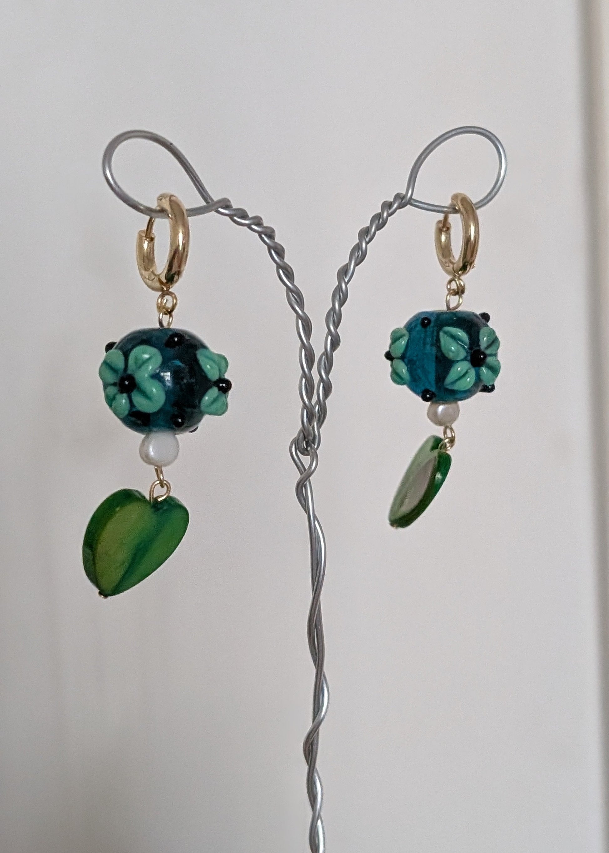 Pair of earrings with green and blue beads on a white background