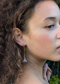 Close-up of a person wearing earrings with a blurred natural background