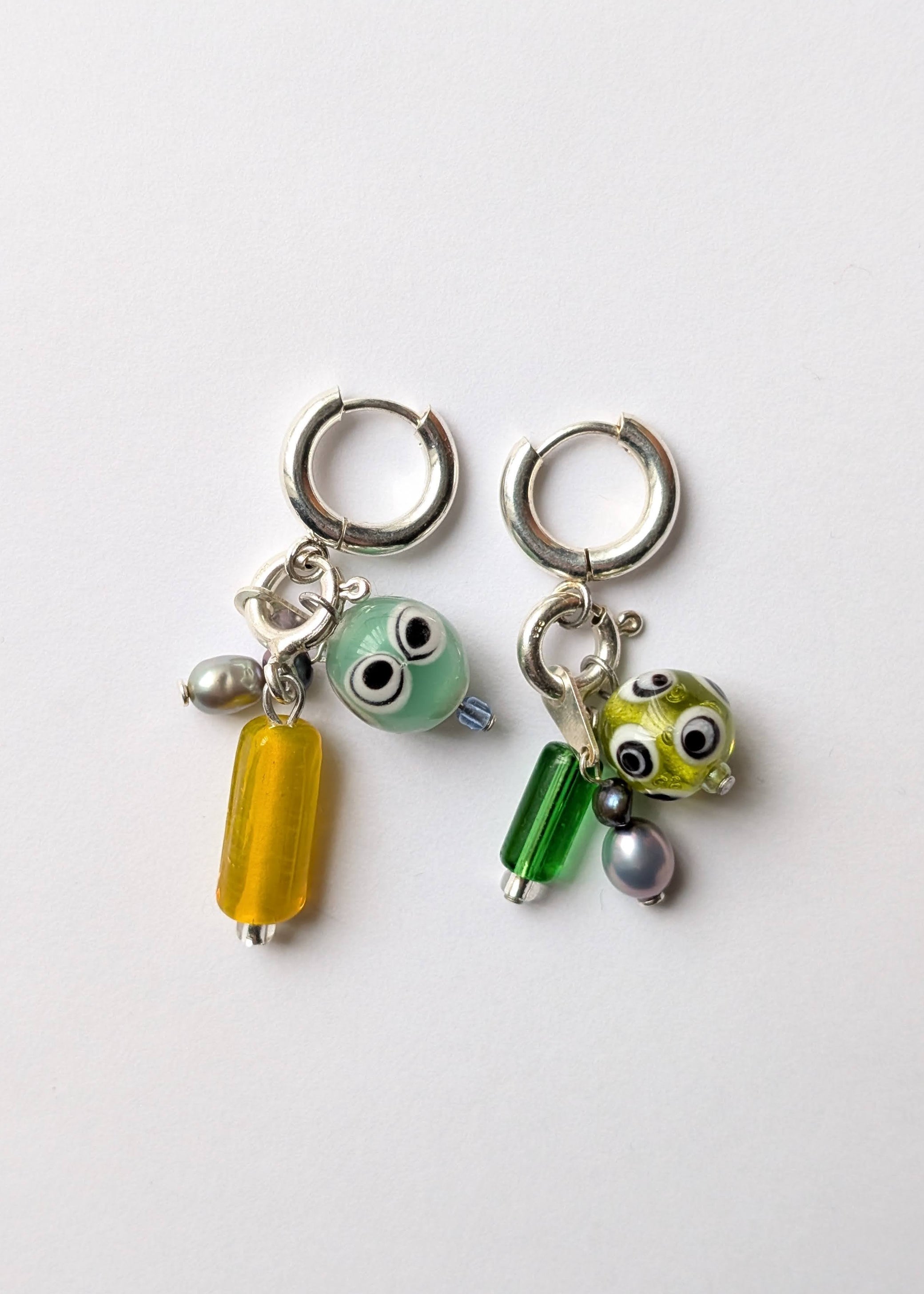 Two small hoop earrings with colorful charms on a white background