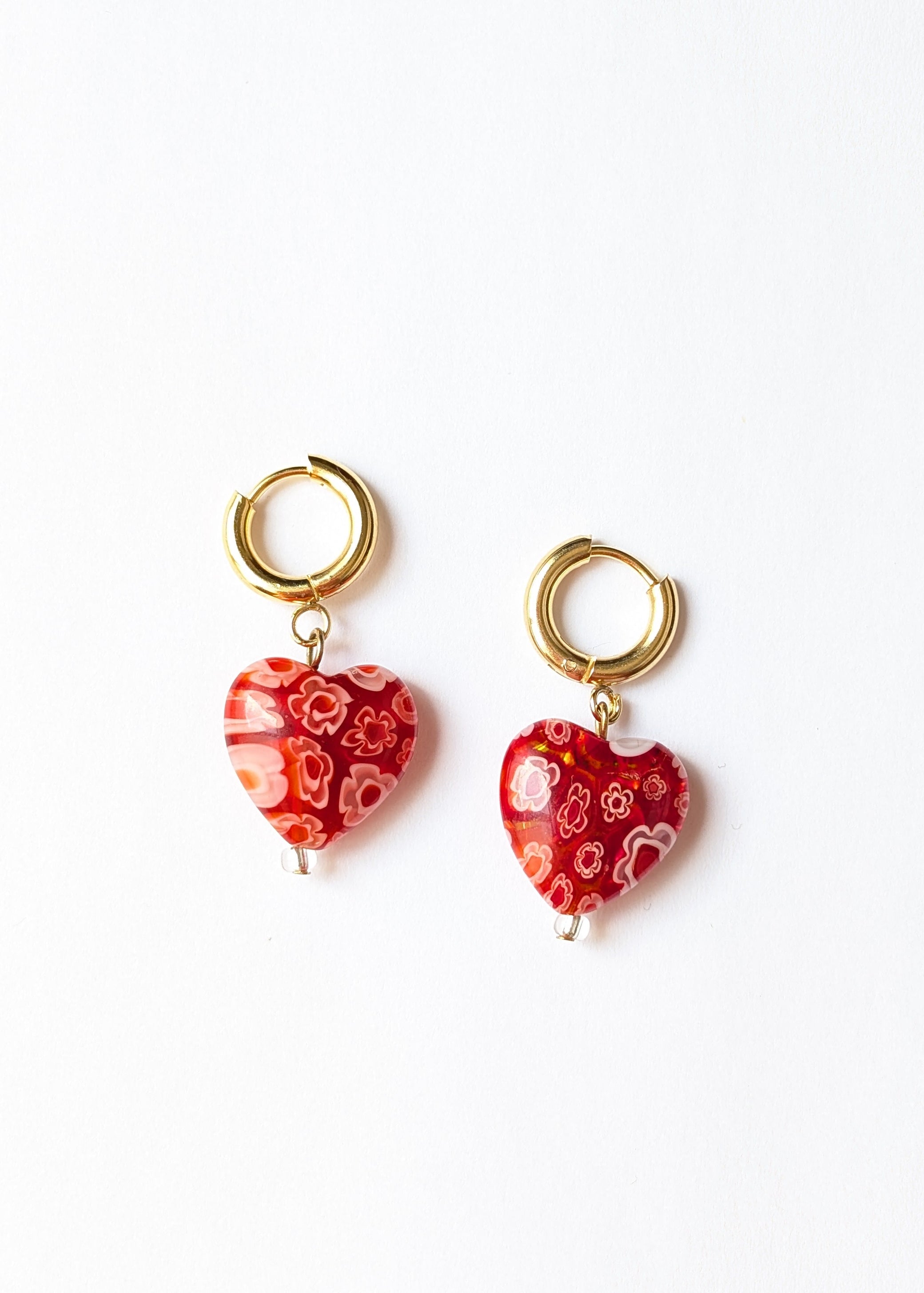 Pair of heart-shaped earrings with floral pattern on a white background