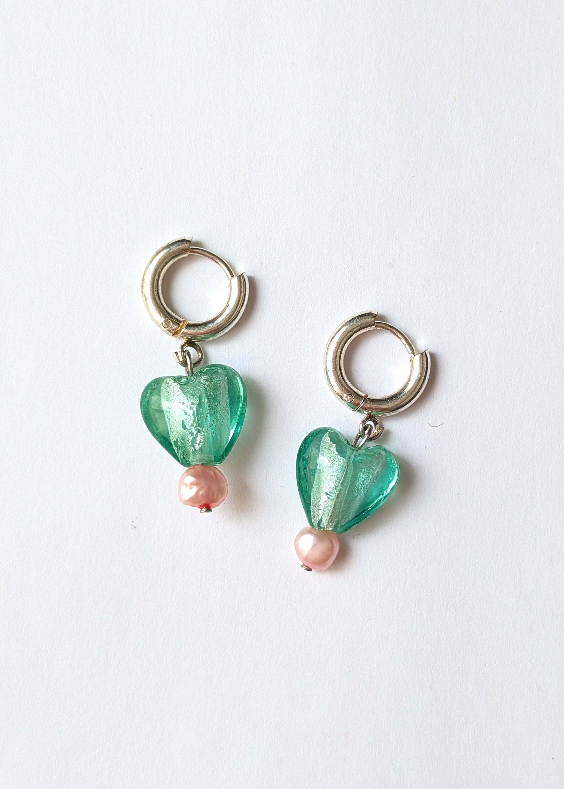 Pair of heart-shaped green earrings with pink beads on a white background