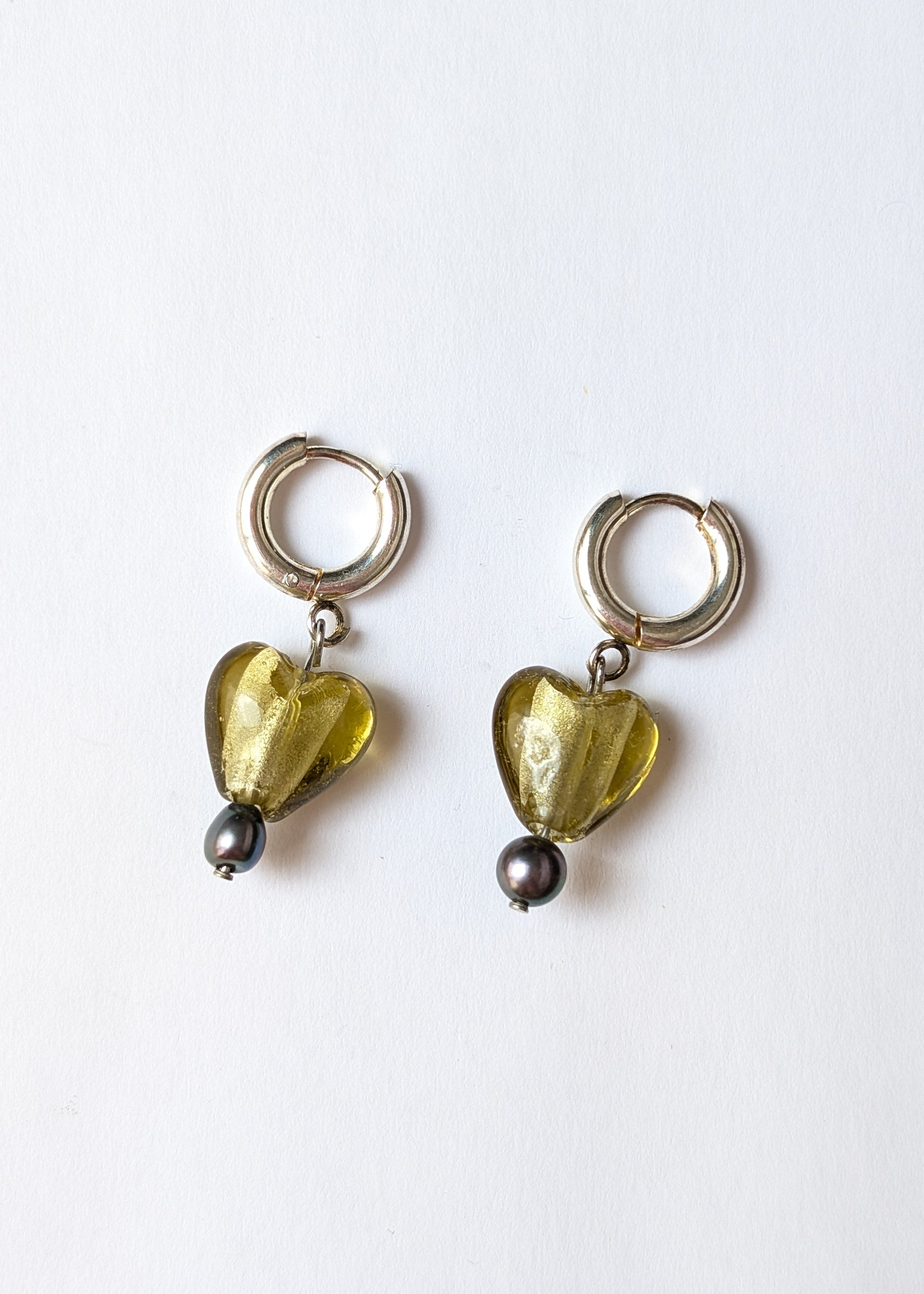 Pair of heart-shaped earrings with green stones on a white background