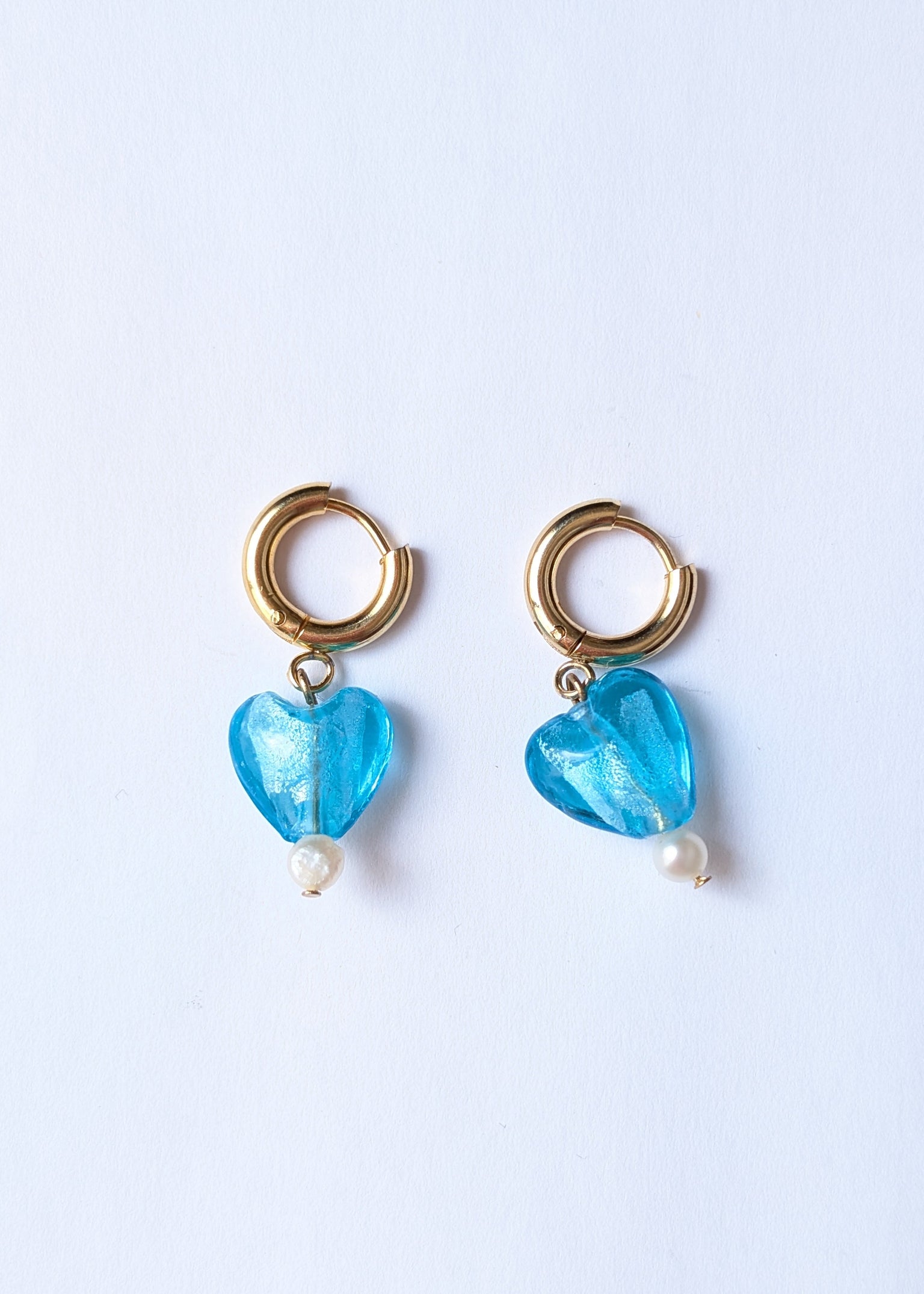 Pair of earrings with blue heart-shaped beads on a white background