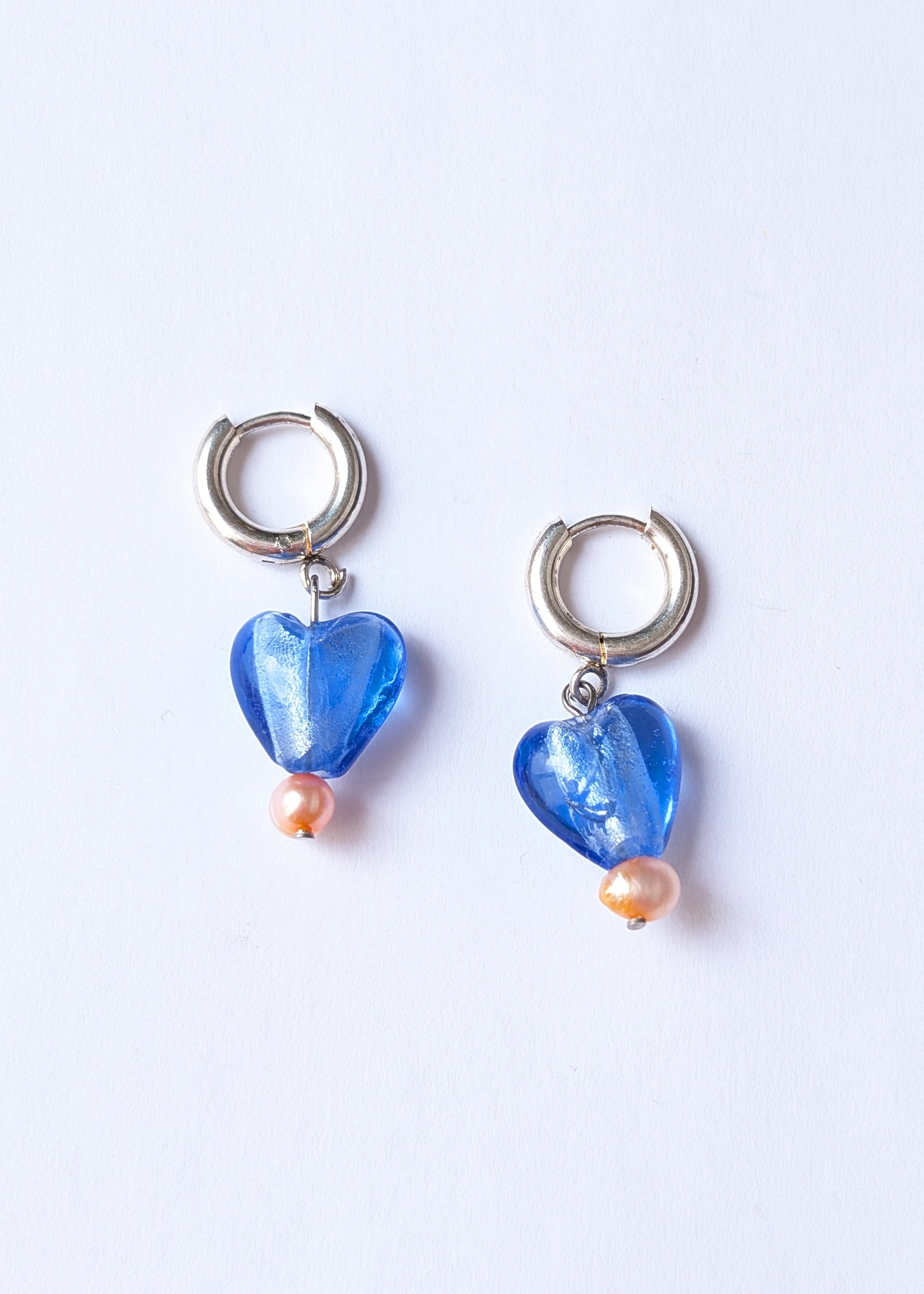 Pair of blue heart-shaped earrings on a light purple background