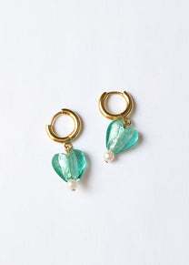 Gold hoop earrings with green heart-shaped beads on a white background