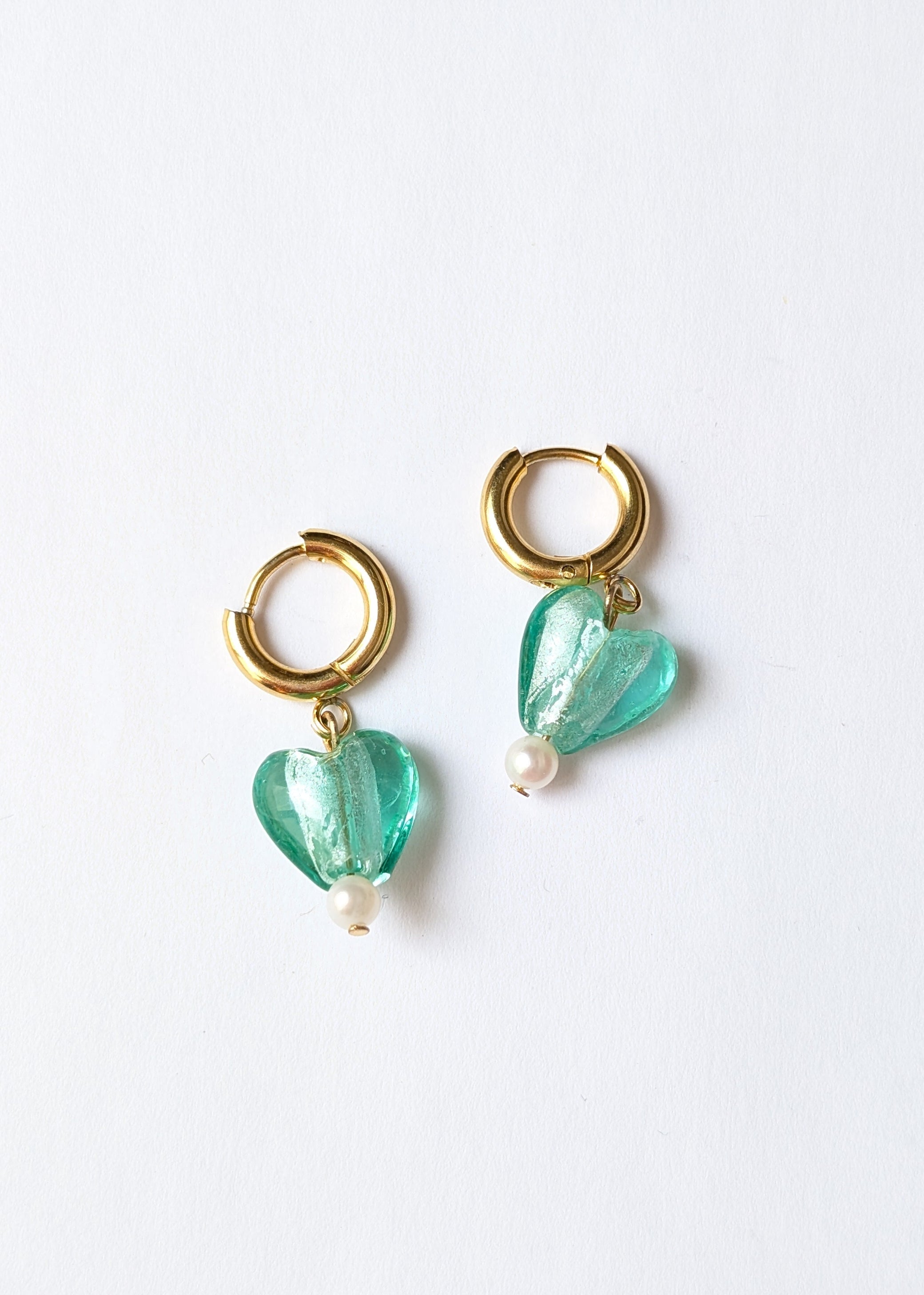 Gold hoop earrings with green heart-shaped beads on a white background