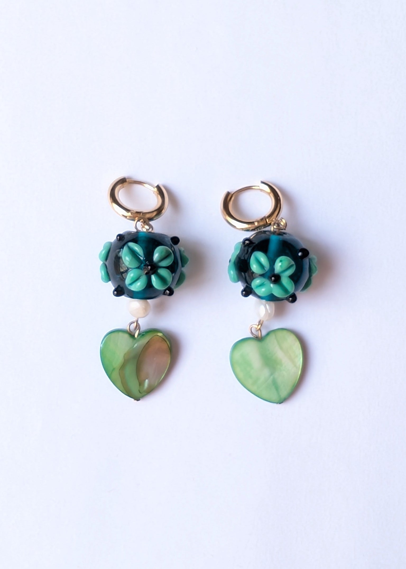 Pair of green floral earrings on a white background