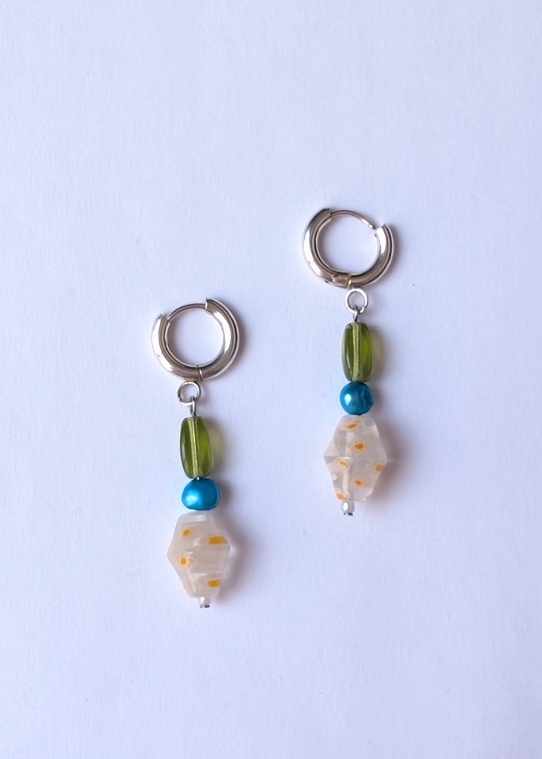 Pair of earrings with beads on a light purple background