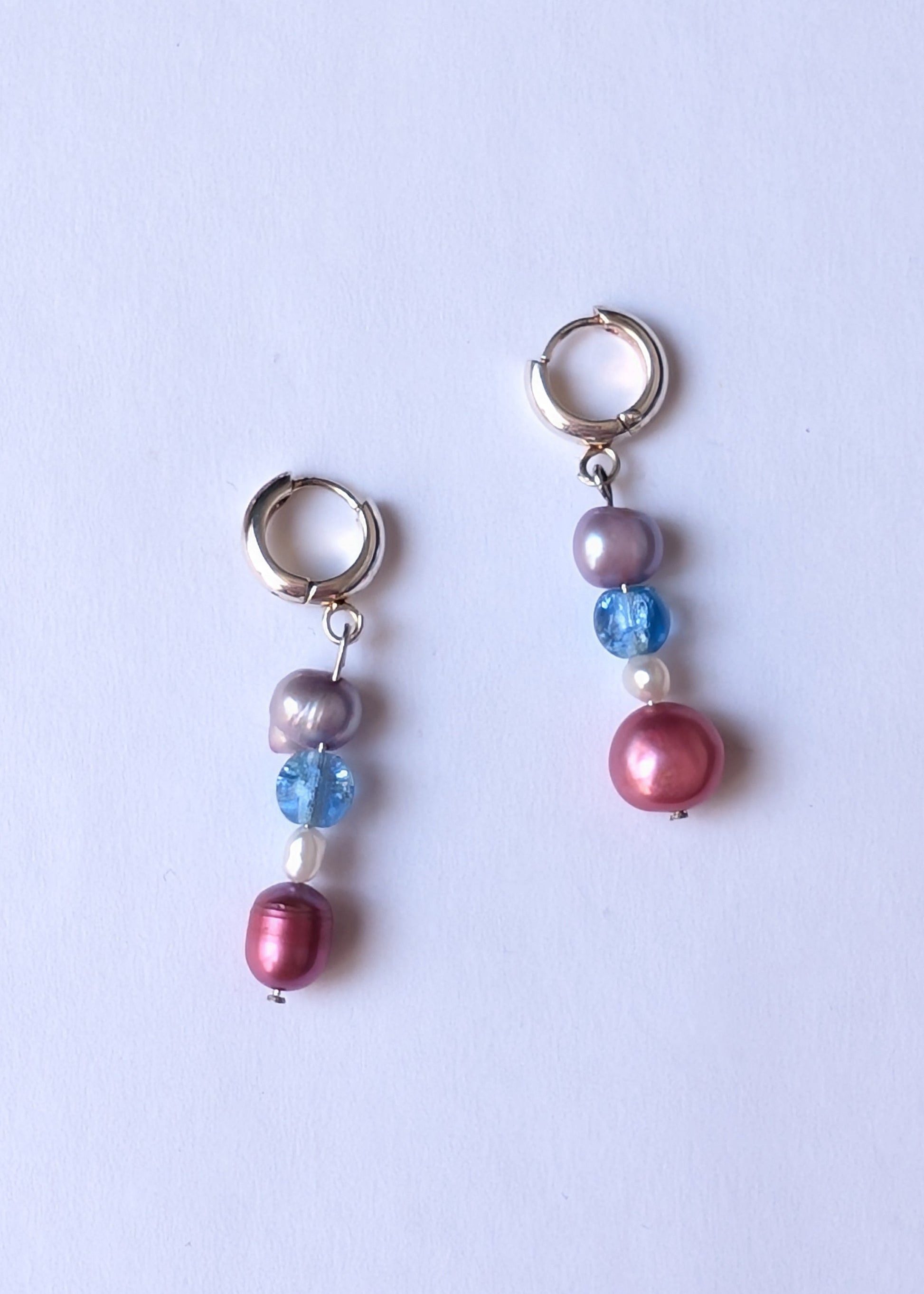 Pair of earrings with multicolored beads on a light purple background