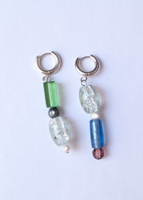 Pair of earrings with colorful beads on a light purple background