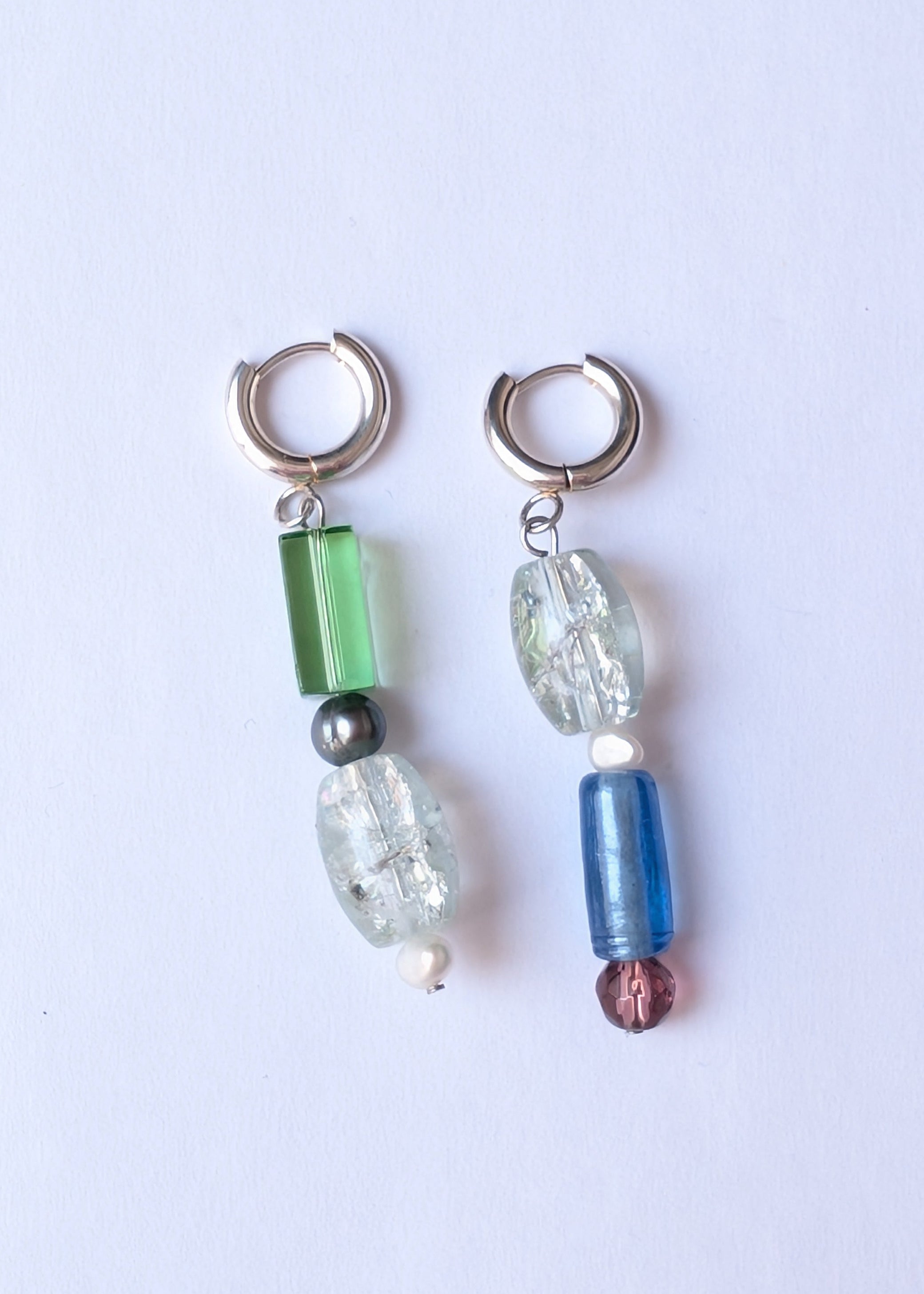 Pair of earrings with colorful beads on a light purple background