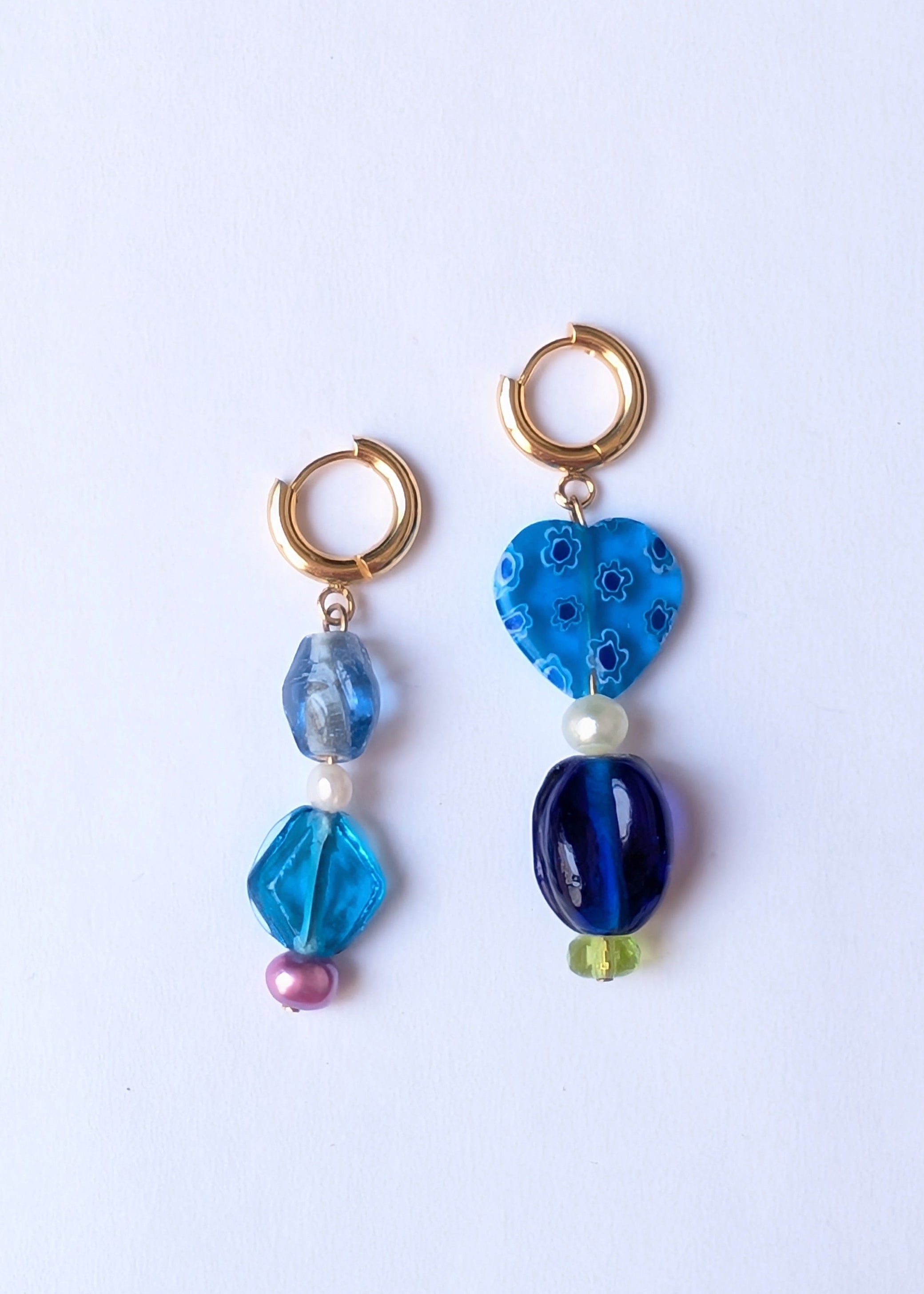 Pair of earrings with blue and gold beads on a white background
