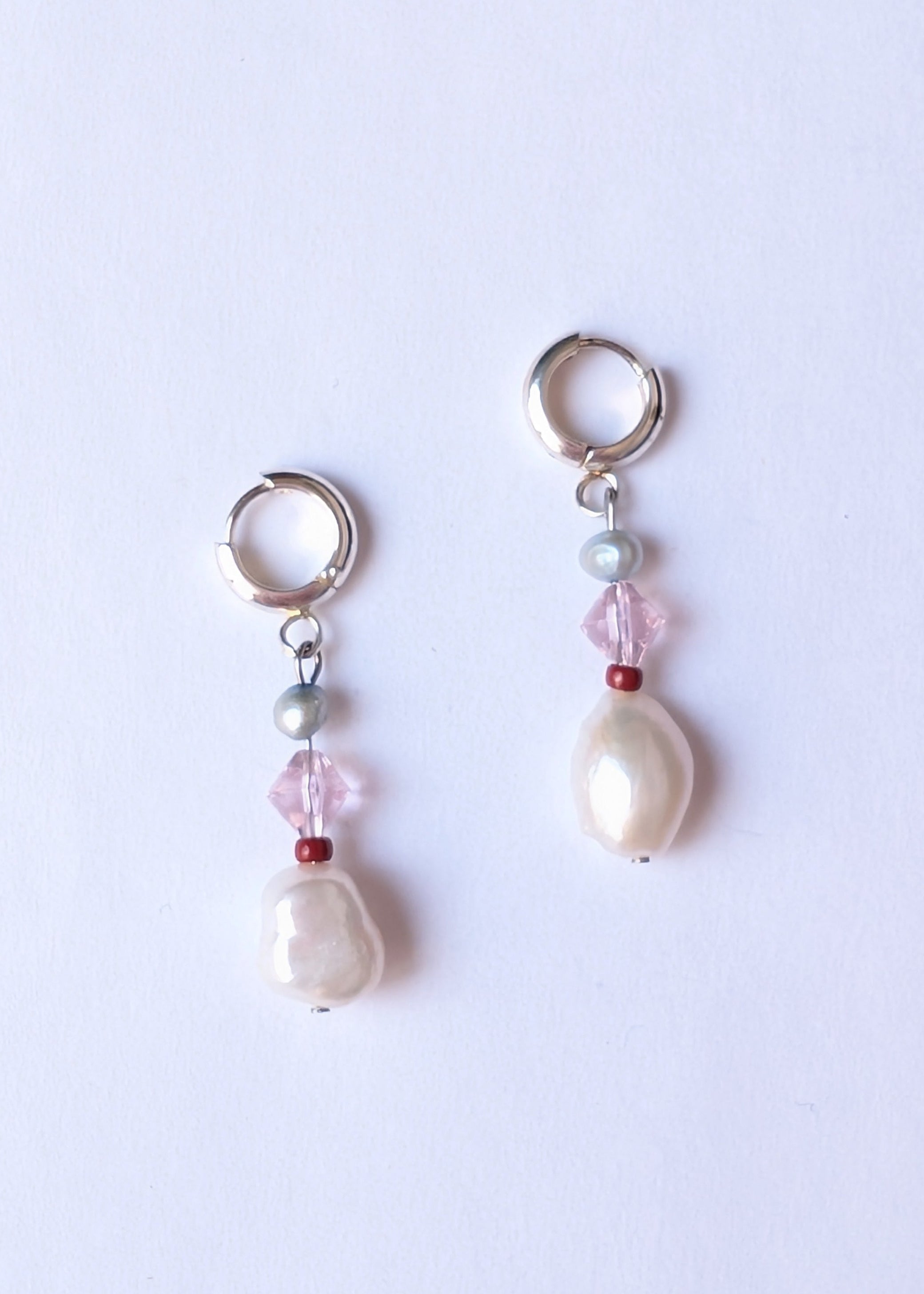 Pair of pearl and bead earrings on a light purple background