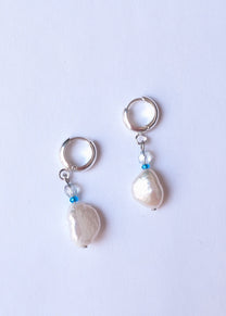 Pair of pearl earrings on a light purple background