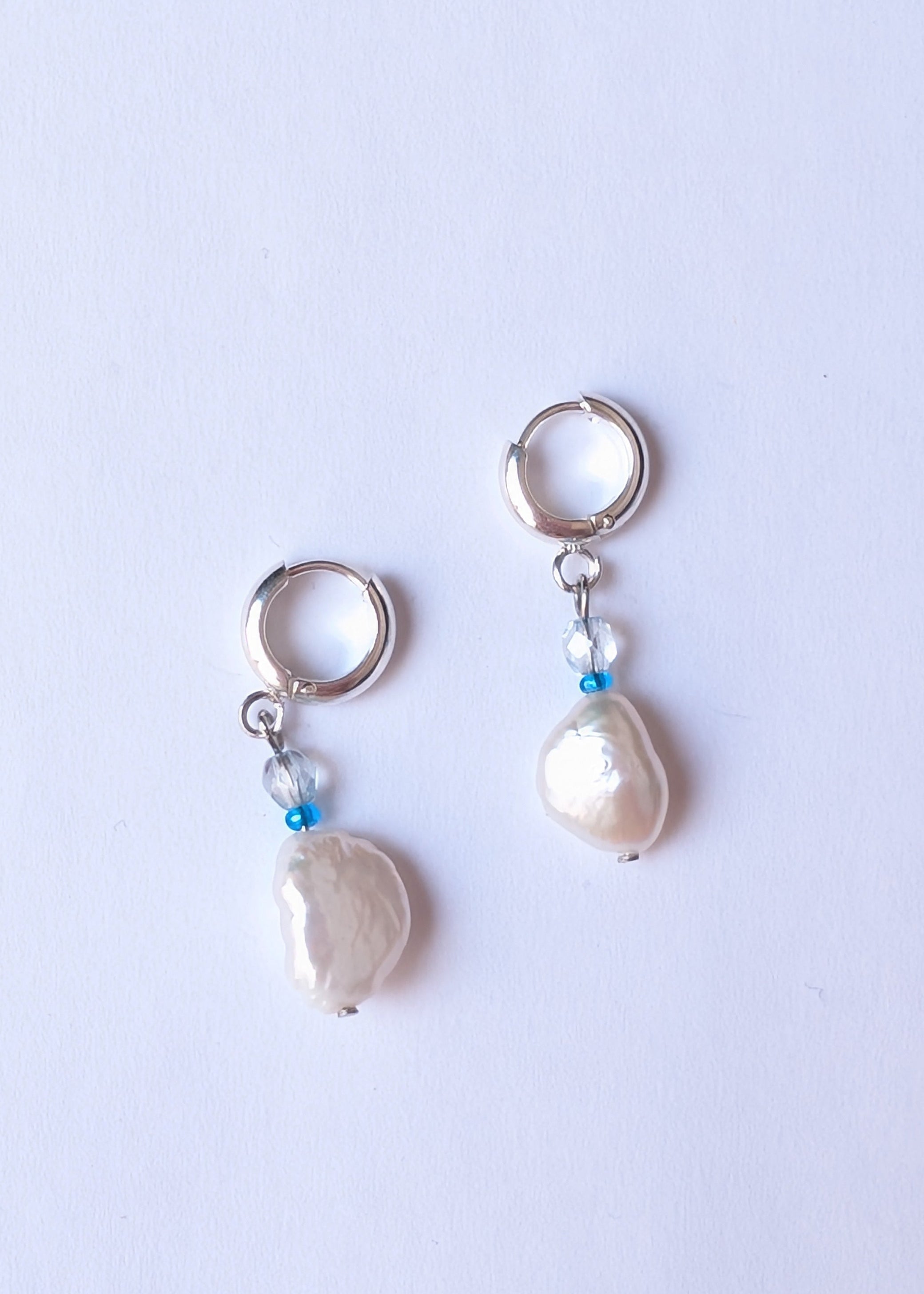 Pair of pearl earrings on a light purple background