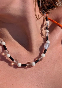 Close-up of a beaded necklace on a person's neck with a blurred background