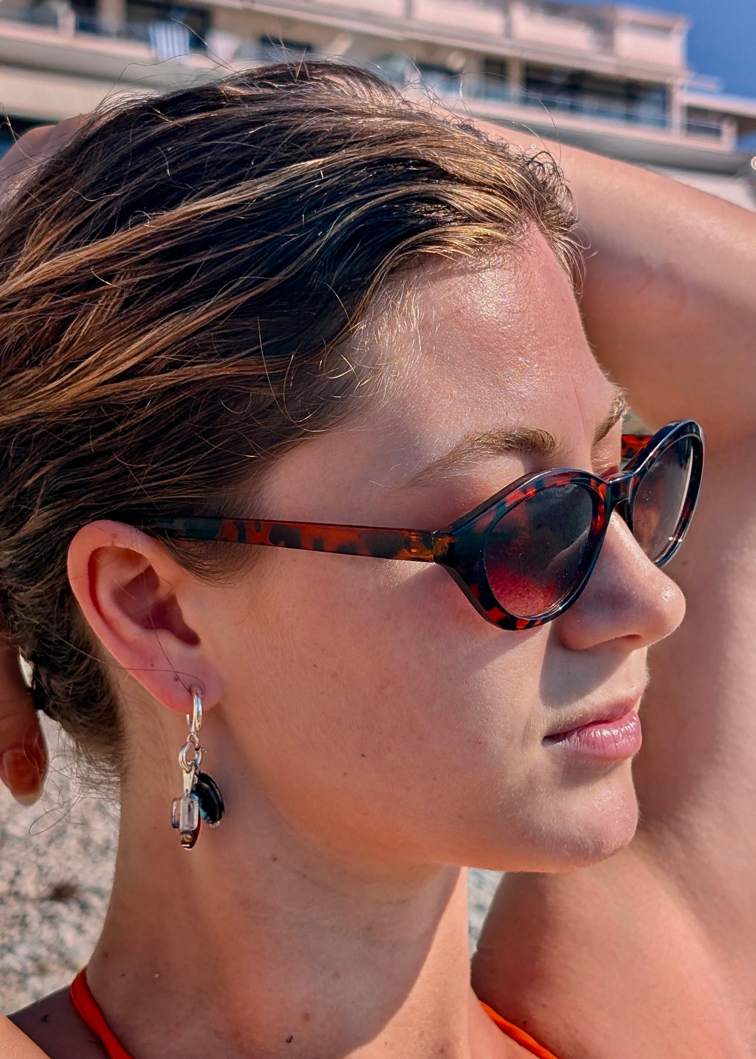 Woman wearing sunglasses and an orange top on a beach