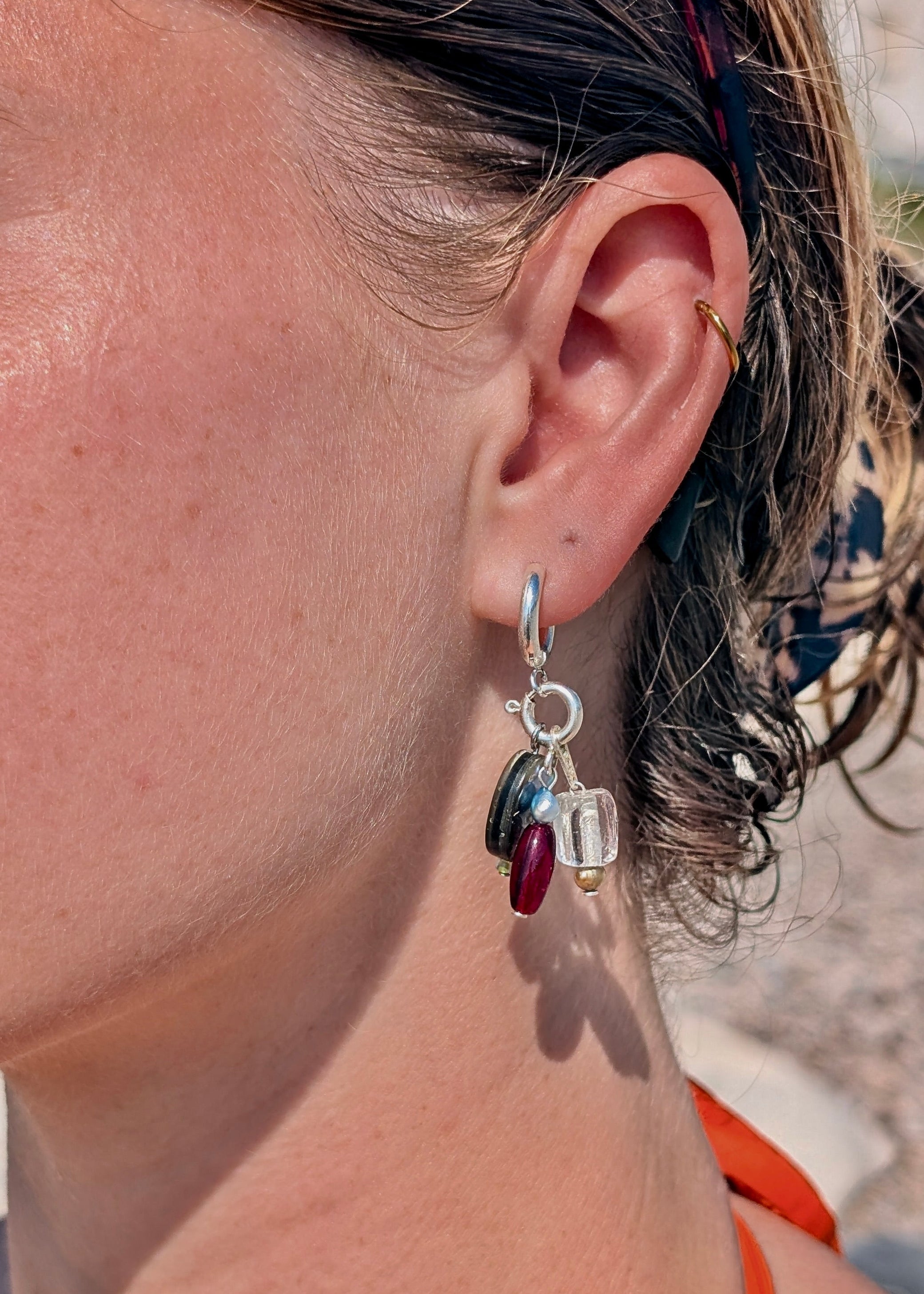 Close-up of an ear wearing a silver earring with colorful beads.